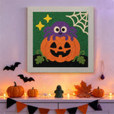 Tableau punch needle araignée perchée accroché au mur parmi des décorations d'Halloween