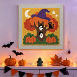 Tableau punch needle arbre au chapeau de sorcière accroché au mur dans une déco d'Halloween