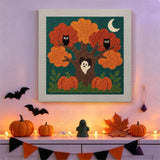 Tableau punch needle arbre aux hiboux accroché au mur dans une déco d'Halloween