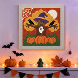 Tableau punch needle arbre au chapeau de sorcière accroché au mur dans une déco d'Halloween