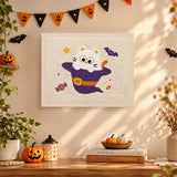 Tableau punch needle chat caché dans un chapeau violet accroché au mur dans une déco d'Halloween