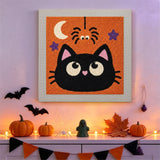 Tableau punch needle chat et araignée accroché au mur dans une déco d'Halloween