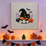 Tableau punch needle chat aux marguerites accroché au mur dans une déco d'Halloween