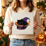 Tableau punch needle chat sorcière tenu en main pour montrer sa taille