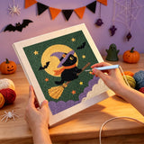 Broderie punch needle en cours, aiguille en main, sur la toile du chat noir volant sur son balai