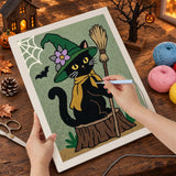 Broderie punch needle en cours sur la toile du chat à l'écharpe jaune, aiguille en main