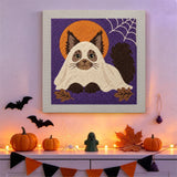 Tableau punch needle chat déguisé en fantôme accroché au mur dans une déco d'Halloween