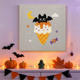 Tableau punch needle cornet gaufré et chauve-souris accroché au mur dans une déco d'Halloween