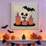 Tableau punch needle crâne et bougies accroché au mur parmi des décorations d'Halloween