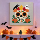 Tableau punch needle crâne d'automne accroché au mur dans une déco d'Halloween