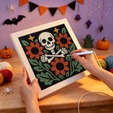 Broderie punch needle en cours, aiguille en main, sur la toile crâne et fleurs rouille