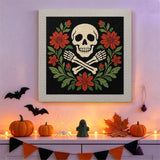 Tableau punch needle crâne et os croisés accroché au mur dans une déco d'Halloween