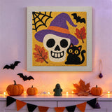 Tableau punch needle crâne au chapeau de sorcière accroché au mur dans une déco d'Halloween