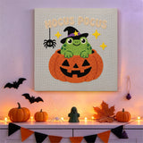 Tableau punch needle crapaud dans sa citrouille accroché au mur dans une déco d'Halloween