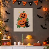 Tableau punch needle citrouilles empilées et chat noir accroché au mur dans une déco d'Halloween