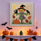 Tableau punch needle épouvantail et chat noir accroché au mur dans une déco d'Halloween