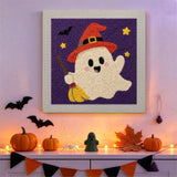 Tableau punch needle fantôme au balai accroché au mur dans une déco d'Halloween