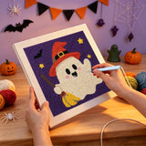 Broderie punch needle en cours, aiguille en main, sur la toile du fantôme au chapeau rouge et son balai