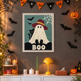 Tableau punch needle fantôme au chapeau rouge accroché au mur dans une déco d'Halloween