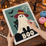 Broderie punch needle en cours sur la toile du fantôme et du mot "Boo", aiguille en main
