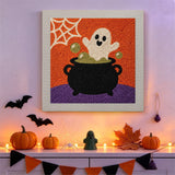 Tableau punch needle fantôme et chaudron accroché au mur dans une déco d'Halloween