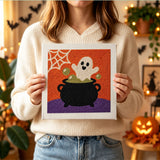 Tableau punch needle chaudron hanté tenu en main pour montrer sa taille