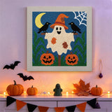 Tableau punch needle fantôme aux corbeaux accroché au mur dans une déco d'Halloween