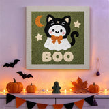 Tableau punch needle fantôme déguisé en chat accroché au mur dans une déco d'Halloween