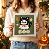 Tableau punch needle fantôme en chat noir tenu en main pour montrer sa taille