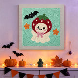 Tableau punch needle fantôme fraise accroché au mur dans une déco d'Halloween