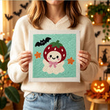 Tableau punch needle fantôme fraise tenu en main pour montrer sa taille