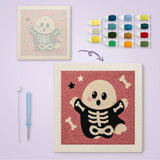 Toile imprimée numérotée à côté du tableau punch needle fantôme en costume de squelette terminé