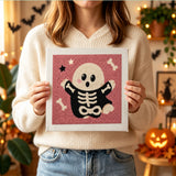 Tableau punch needle fantôme osseux tenu en main pour montrer sa taille