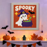 Tableau punch needle fantôme au chaudron accroché au mur dans une déco d'Halloween