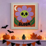 Tableau punch needle fleur tête de mort accroché au mur dans une déco d'Halloween