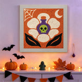 Tableau punch needle fleur potion accroché au mur dans une déco d'Halloween