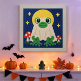Tableau punch needle grenouille fantôme et champignons accroché au mur dans une déco d'Halloween