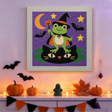 Tableau punch needle grenouille sorcière accroché au mur dans une déco d'Halloween