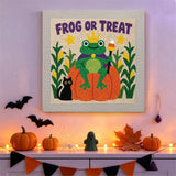 Tableau punch needle grenouille roi au mur d'une pièce décorée pour Halloween