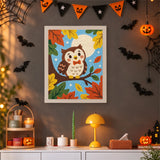 Tableau punch needle hibou sur sa branche accroché au mur dans une déco d'Halloween