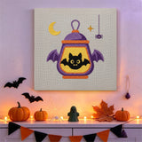 Tableau punch needle lanterne ailée accroché au mur dans une déco d'Halloween