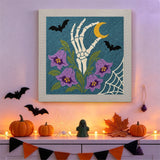 Tableau punch needle main et campanules accroché au mur parmi des décorations d'Halloween