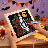 Broderie punch needle en cours, aiguille en main, sur la toile de la bougie et des coquelicots