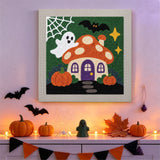 Tableau punch needle maison amanite accroché au mur parmi des décorations d'Halloween