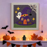 Tableau punch needle maison chapeau de sorcière accroché au mur dans une déco d'Halloween