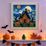 Tableau punch needle maison hantée et chat noir accroché au mur dans une déco d'Halloween