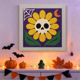 Tableau punch needle marguerite crâne accroché au mur dans une déco d'Halloween