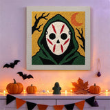 Tableau punch needle masque à capuche accroché au mur parmi des décorations d'Halloween