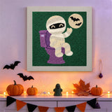 Tableau punch needle momie aux toilettes accroché au mur dans une déco d'Halloween