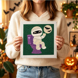 Tableau punch needle momie farceuse tenu en main pour montrer sa taille